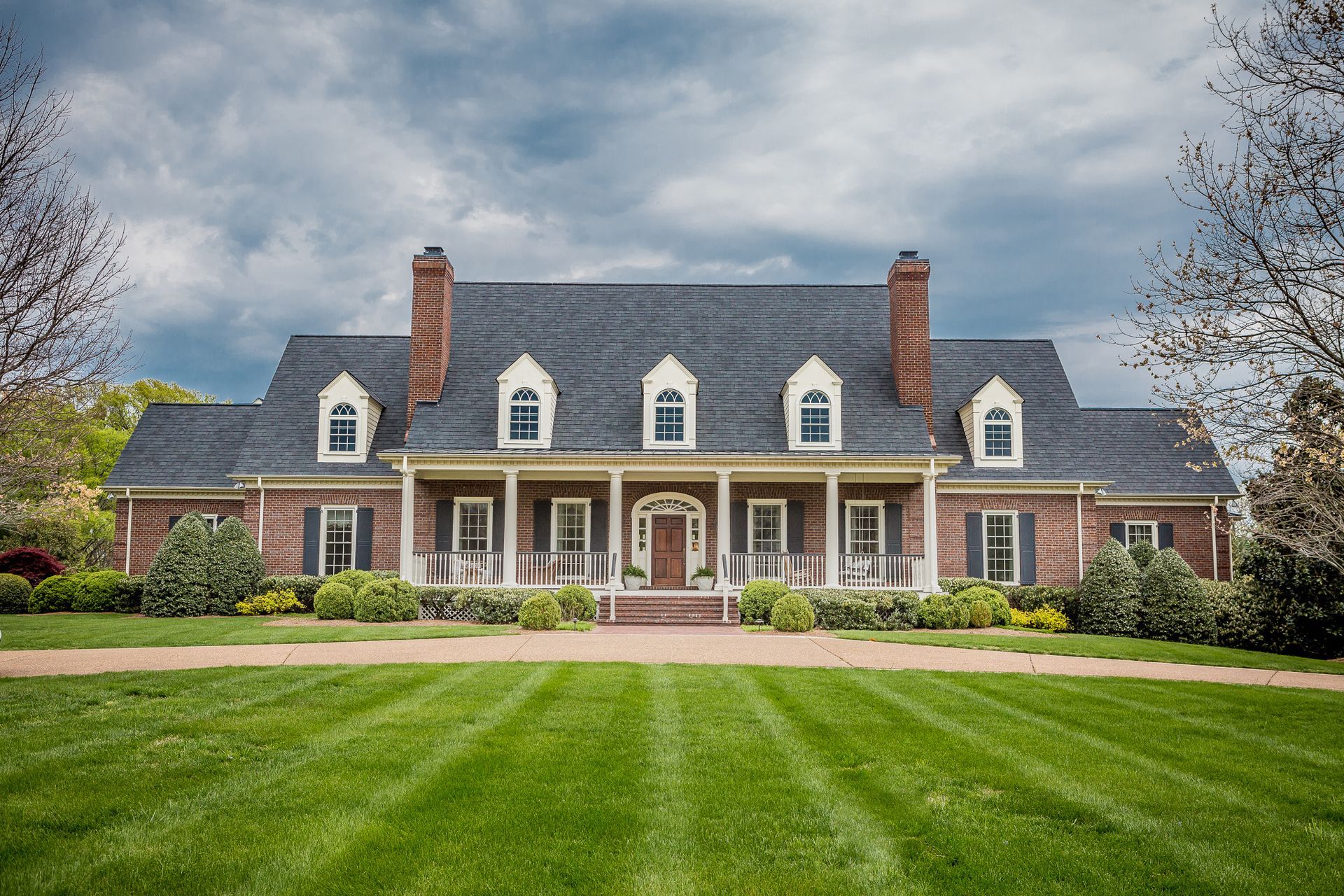 A large brick house with a lush green lawn in front of it.