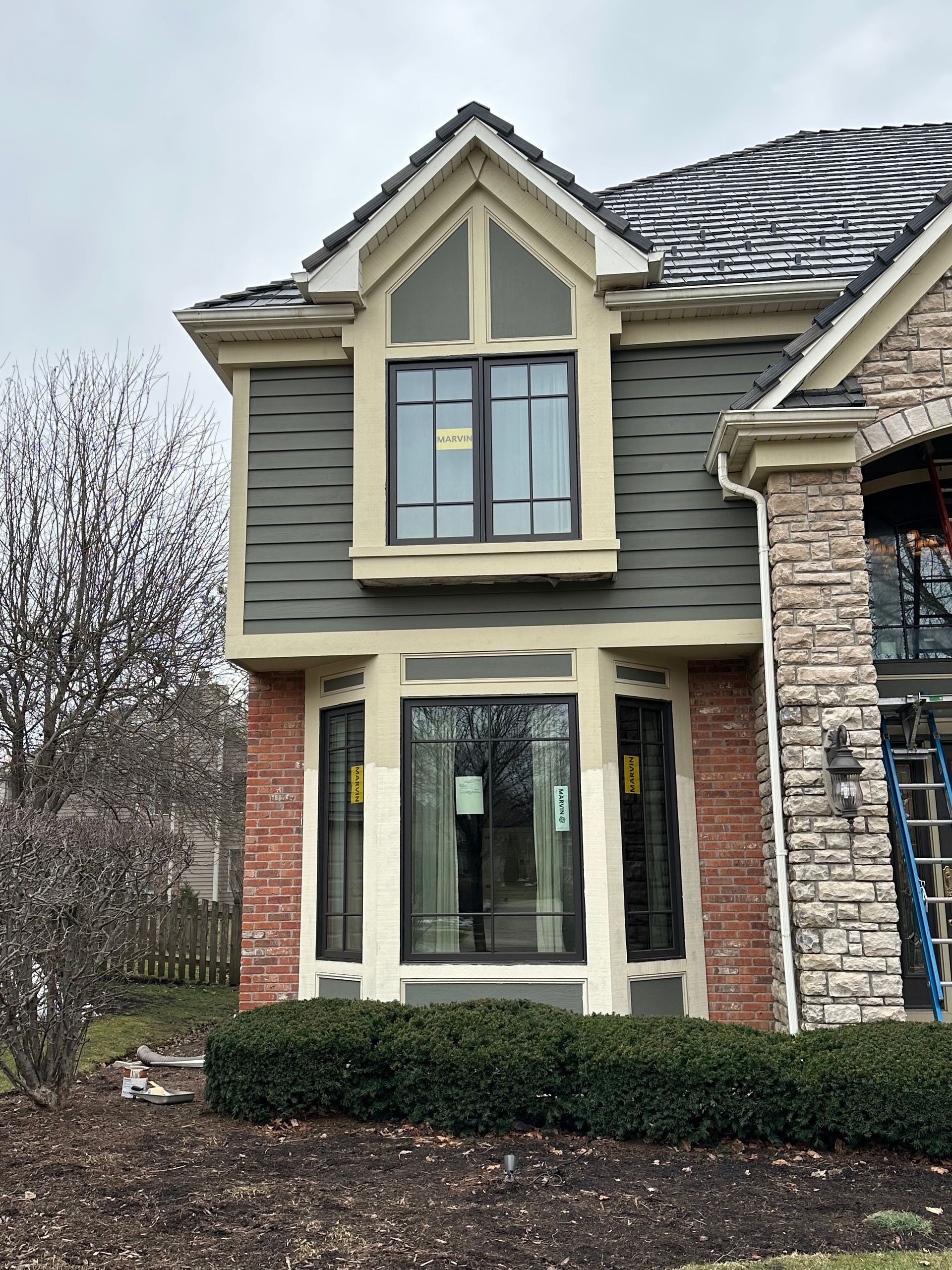 House exterior with brick, gray siding, and a multi-pane window.