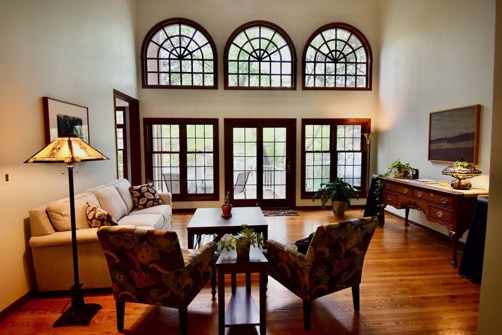 A living room with a couch and chairs and lots of windows