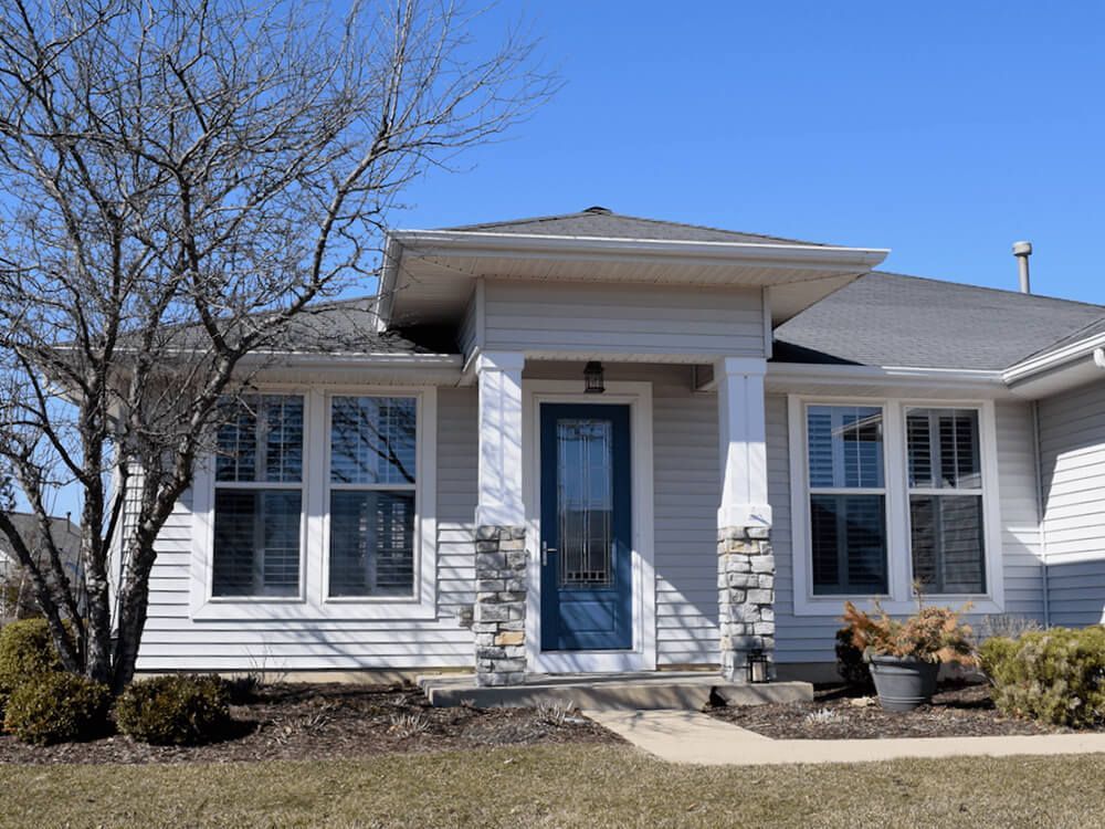 The front of a white house with a blue door and windows.