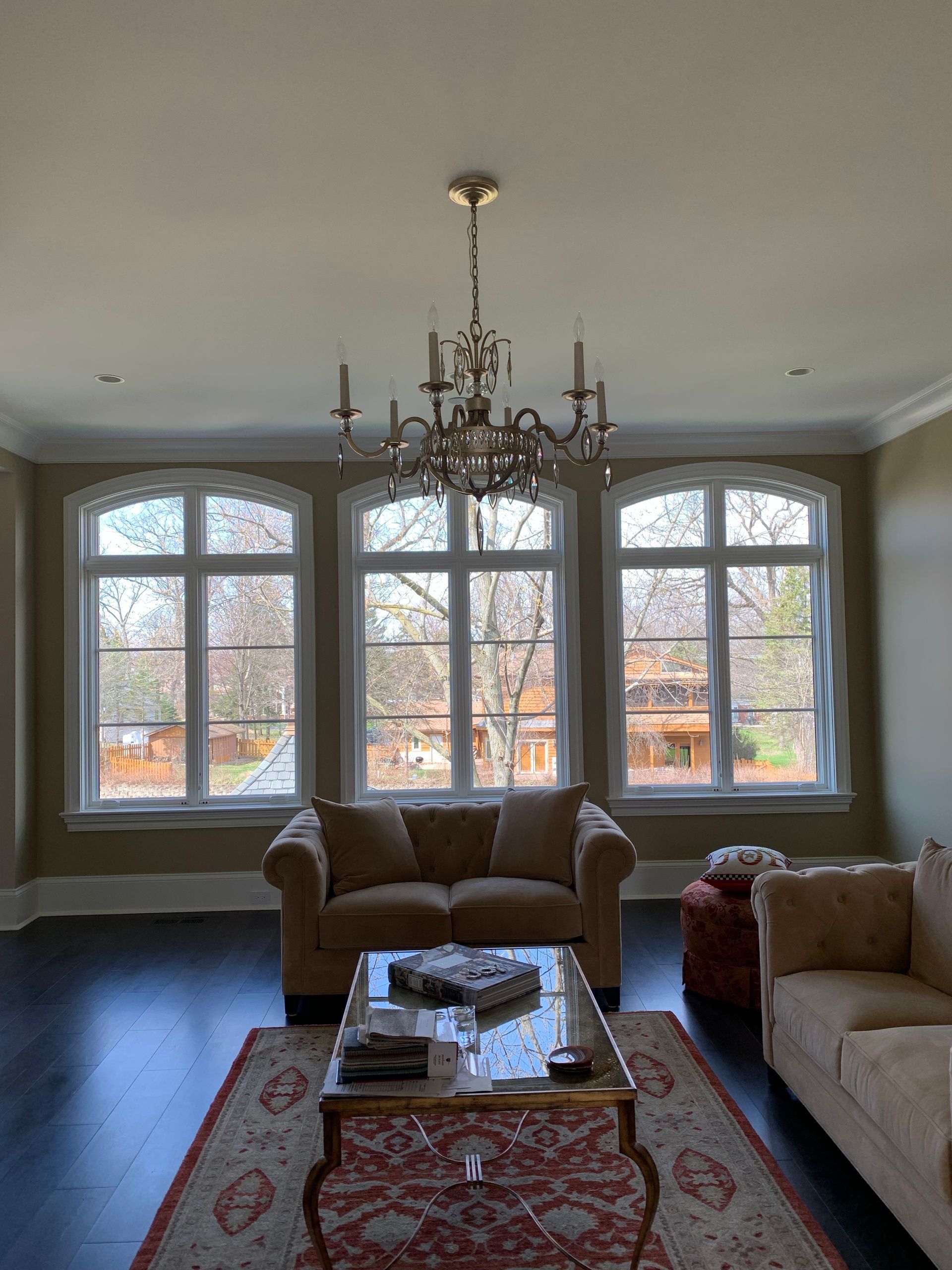 Living room with three arched windows, a chandelier, and a seating area with a sofa and rug.
