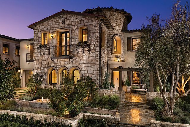 A large stone house with a lot of windows is lit up at night