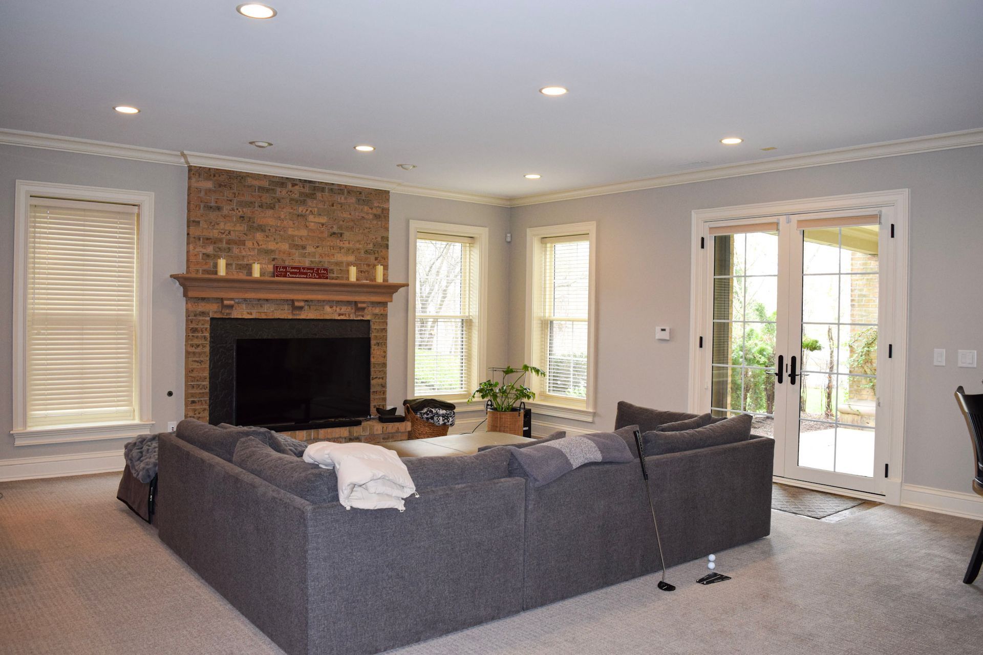 Living room with gray sectional sofa, brick fireplace, and French doors.