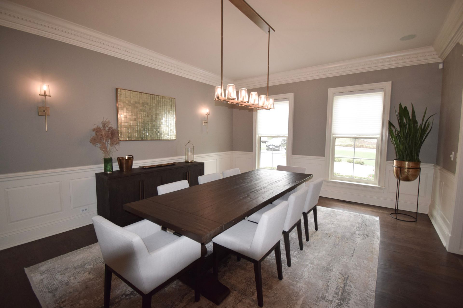 Elegant dining room with a dark wood table, white chairs, and gray walls.
