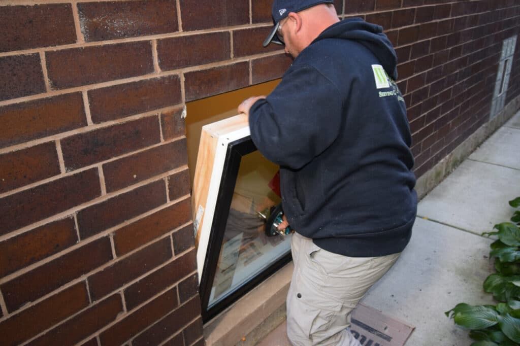 A man is installing a window in a brick wall