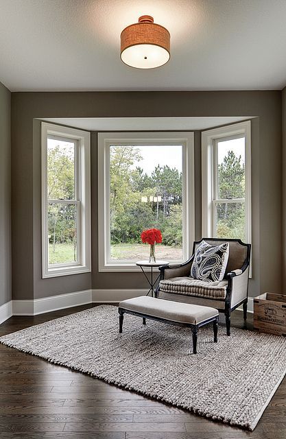 A living room with a chair and ottoman in front of a bay window.