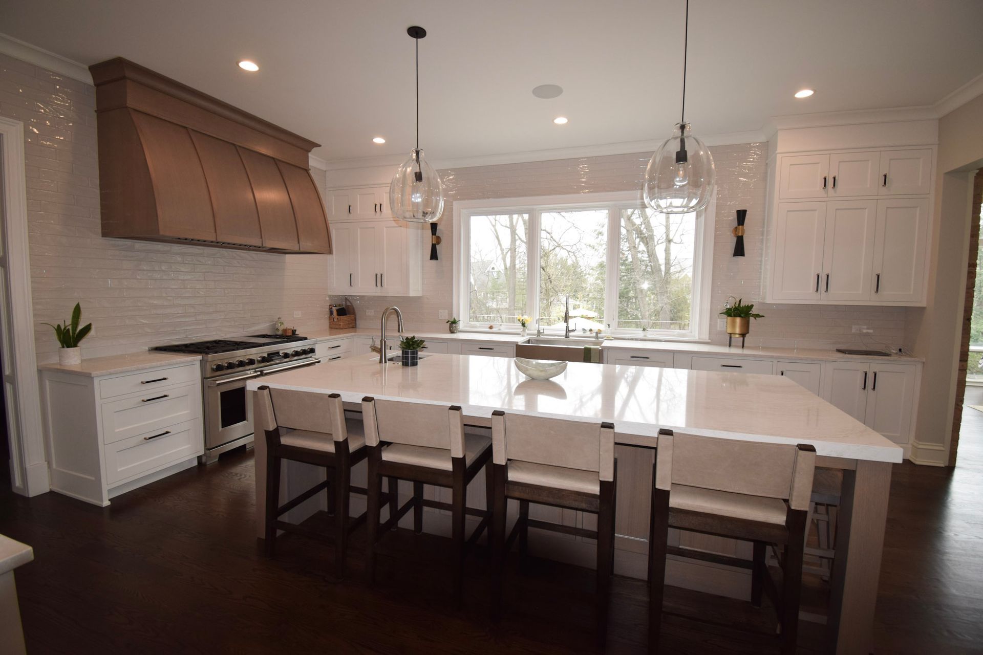 Modern white kitchen with large island, white cabinets, and dark wood floor.