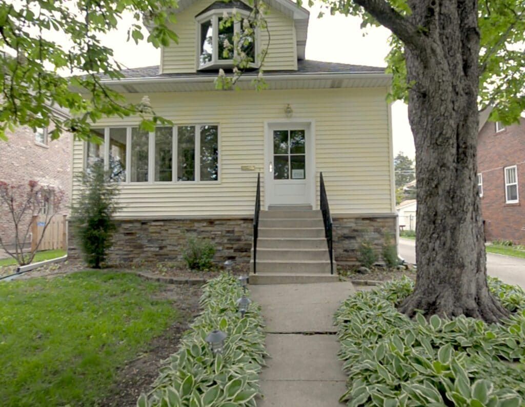 A yellow house with a tree in front of it