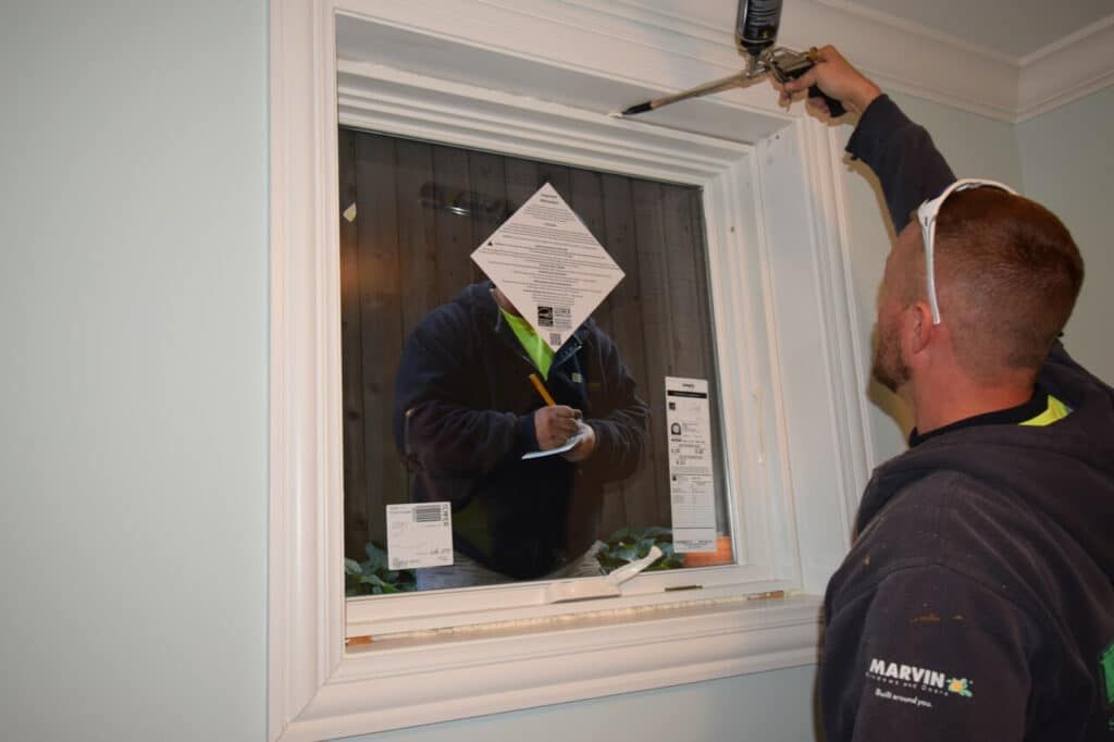 A man is installing a window in a house.