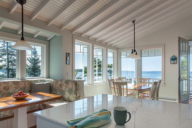 A kitchen with a lot of windows and a coffee mug on the counter.