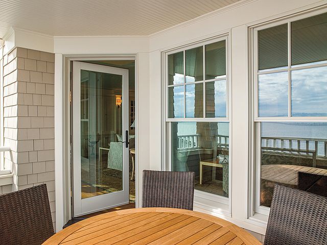 There is a table and chairs on the balcony with a view of the ocean.