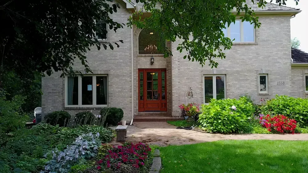 A large brick house with a wooden door and a lush green lawn.