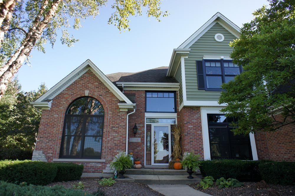 A large brick house with a green siding and black windows