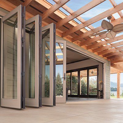 An outdoor patio space with a lot of windows and a ceiling fan.