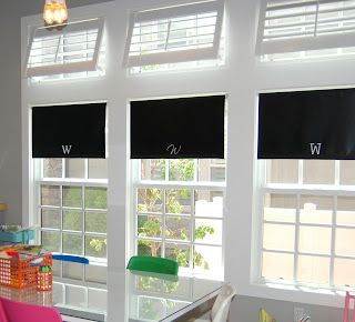 A room with three windows with black blinds and a desk.