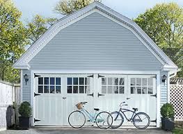 Two bicycles are parked in front of a white garage door.