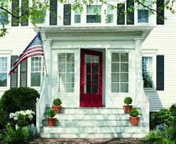 A white house with a red door and an american flag on the porch.