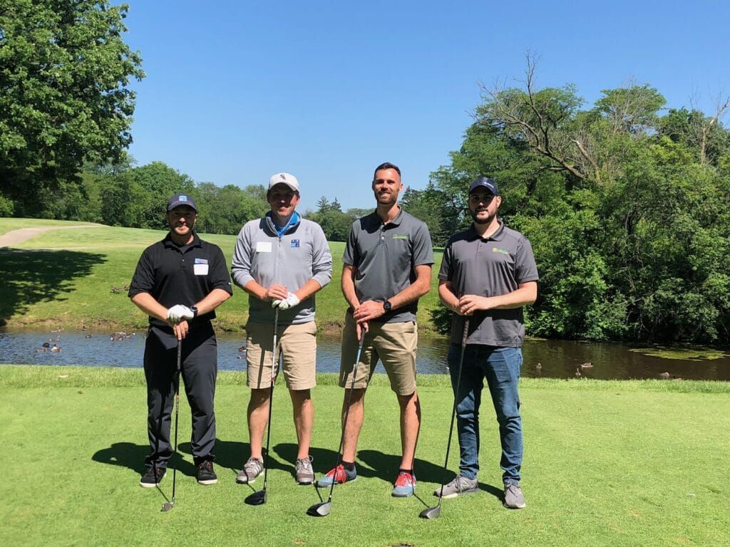 A group of men are standing on a golf course holding golf clubs.