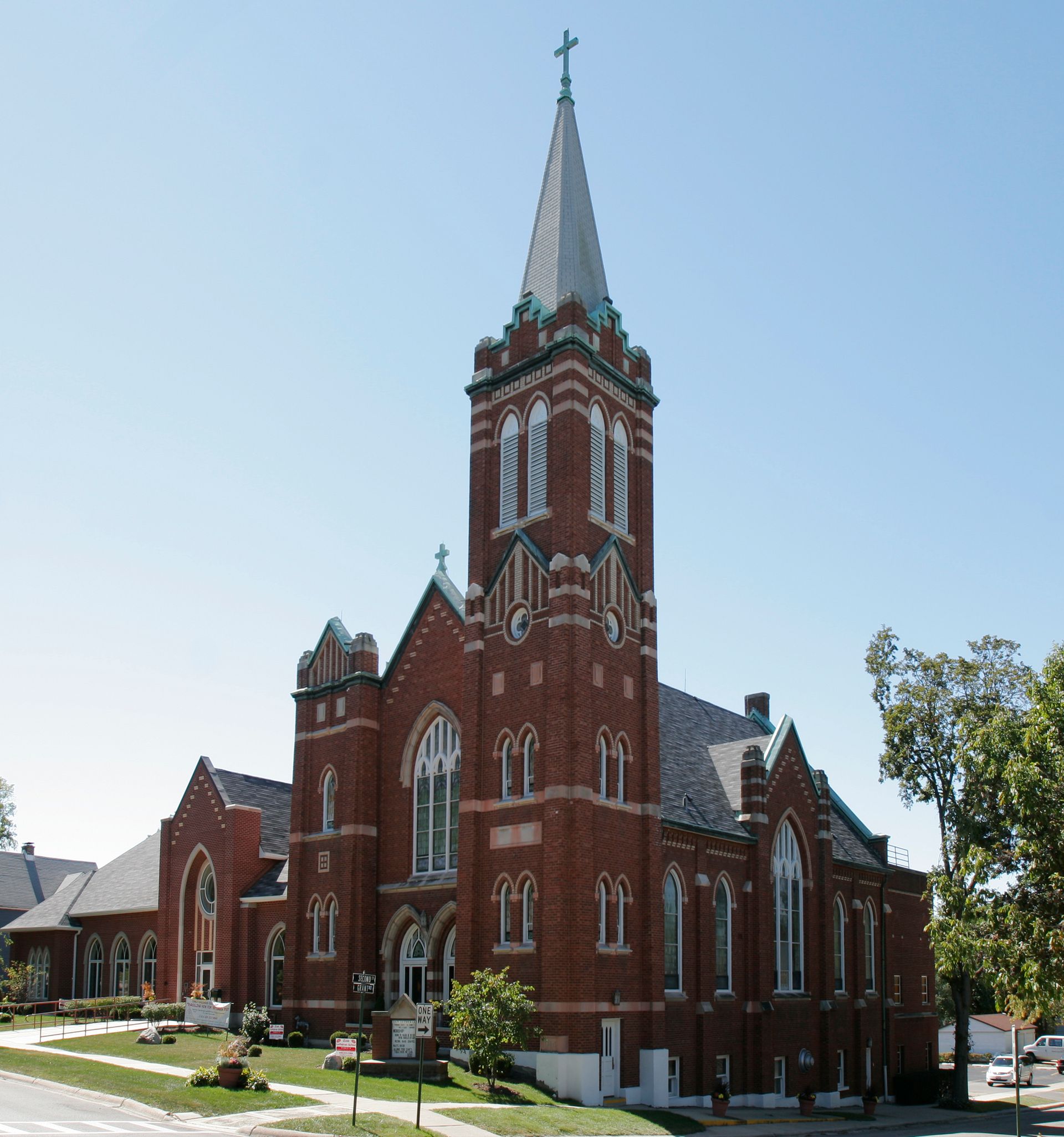 A large red brick church with a steeple and a cross on top
