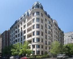 A large building with a lot of windows is sitting on the corner of a city street.