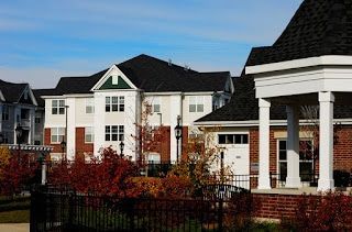 A large apartment building with a porch and a fence in front of it.