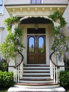 A white house with a porch and stairs leading to the front door.