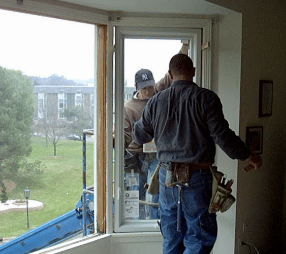 2 men are working on installing a window