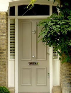 A white front door with a tree in front of it.