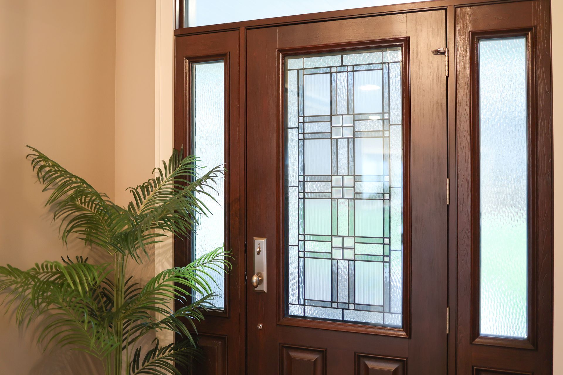 A wooden door with a stained glass window and a plant in front of it.