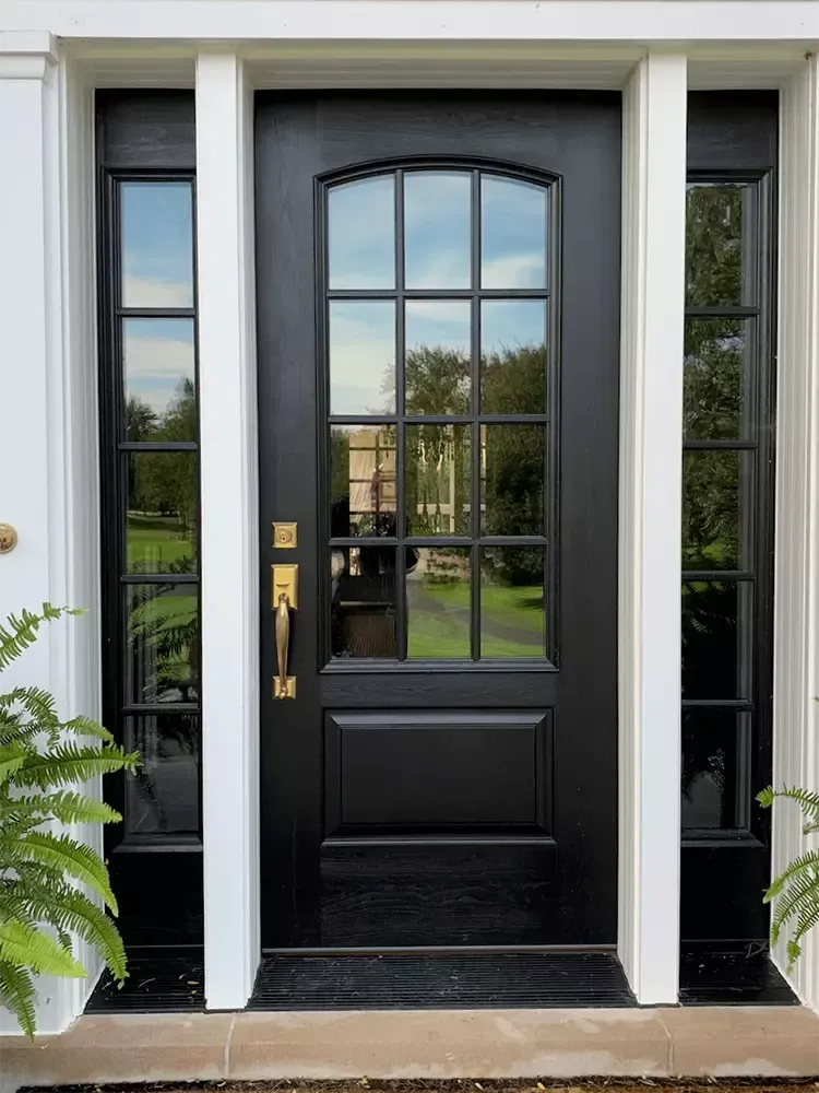 A black front door with a lot of windows on a white house.