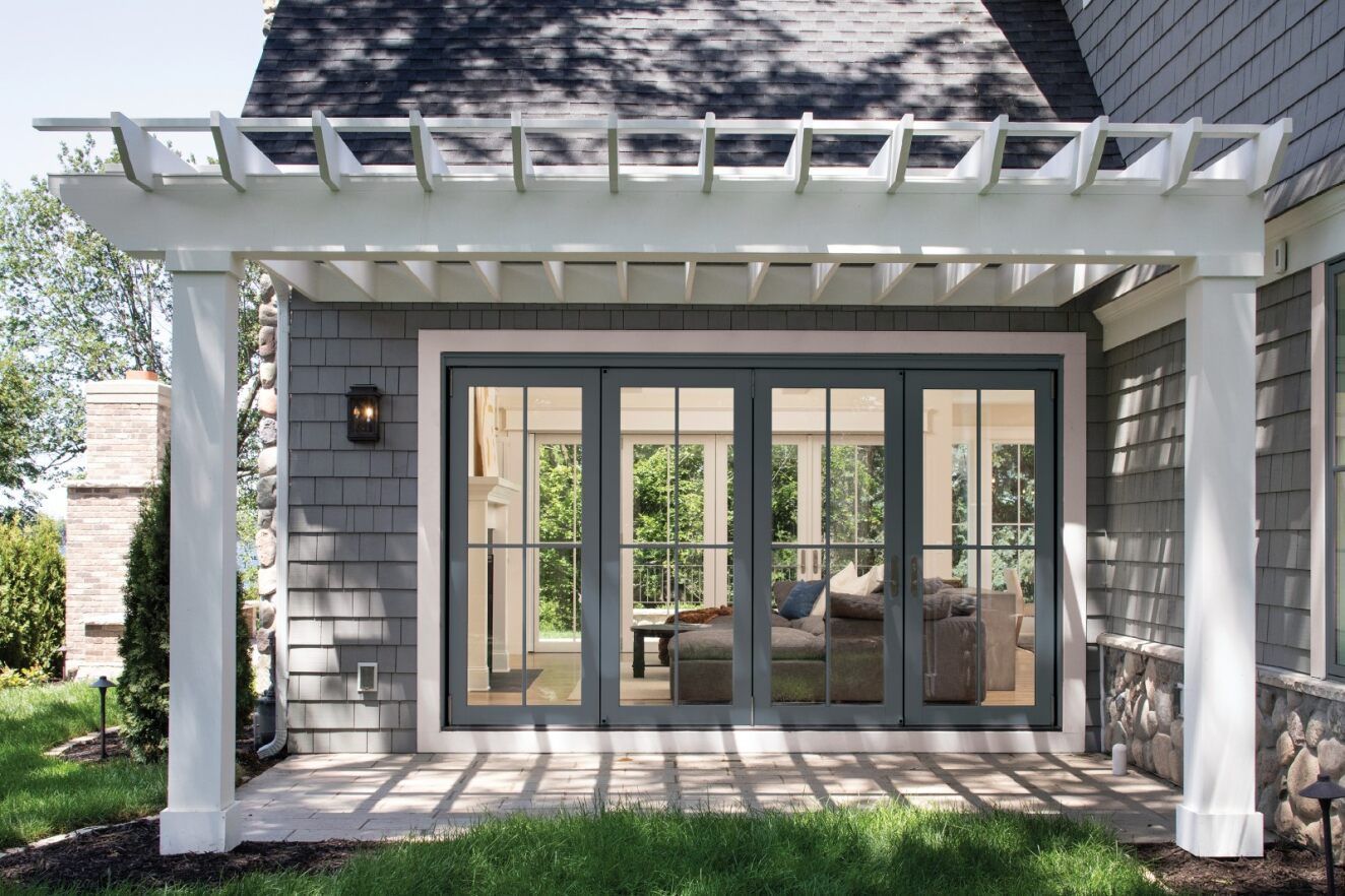 A house with a pergola and sliding glass doors.