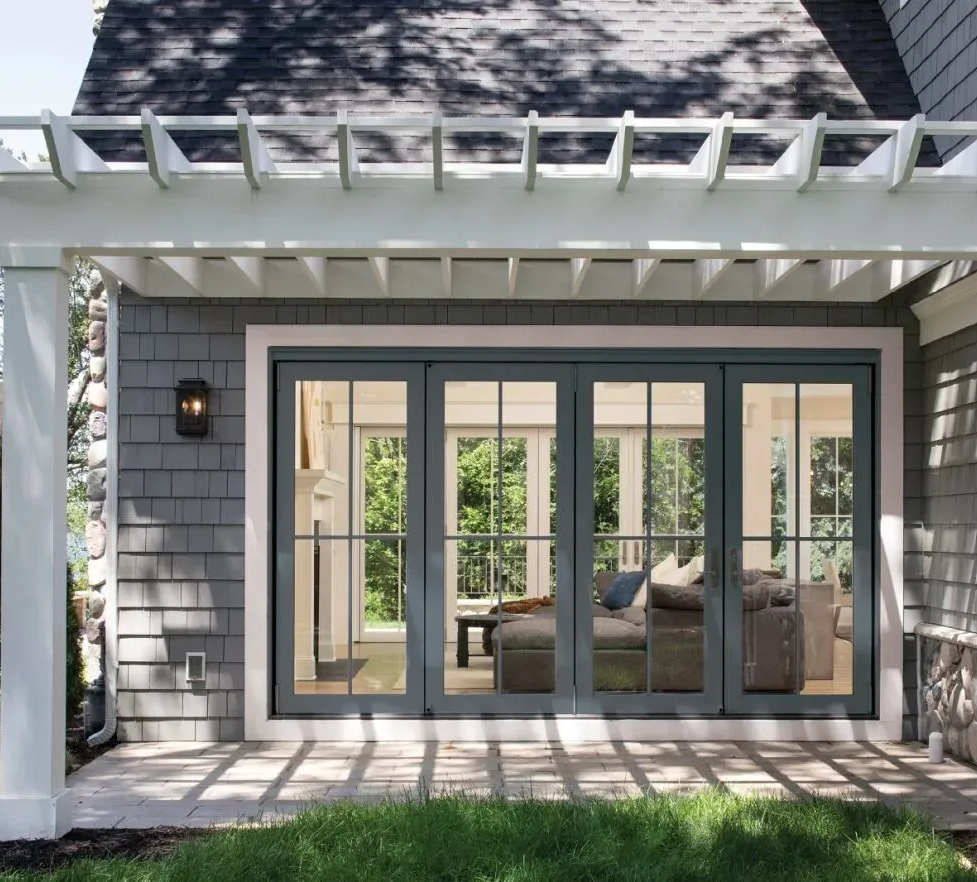 A white-framed, double-hung window with a grid pattern, showing a view of a porch, trees, and a car outside.