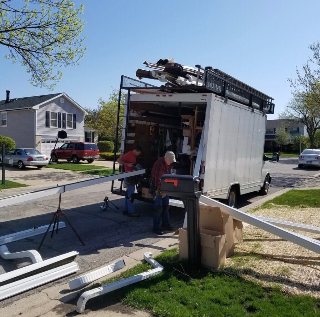 A white van with a ladder on top of it is parked on the side of the road.