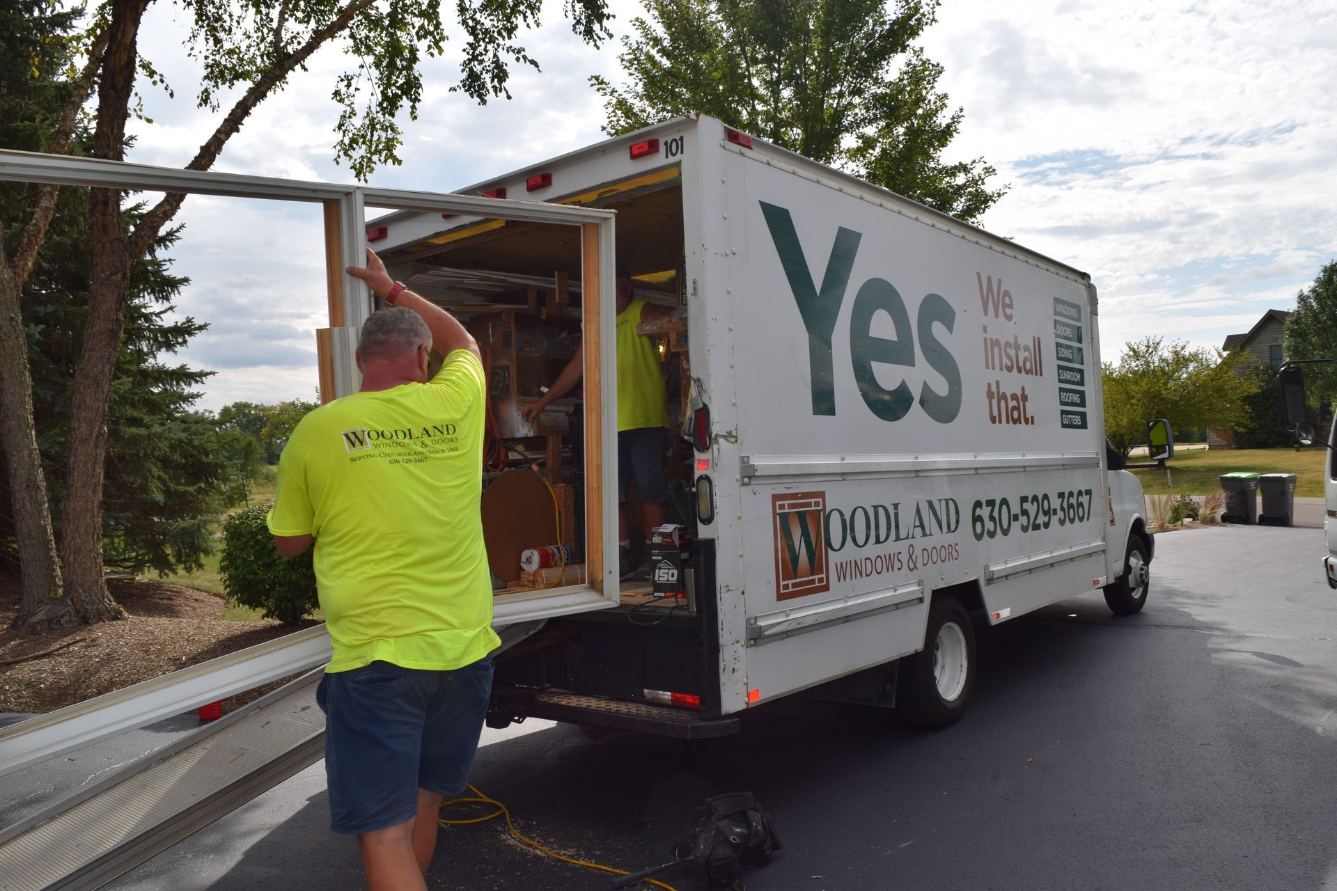 A man in a yellow shirt is standing in front of a yes truck.