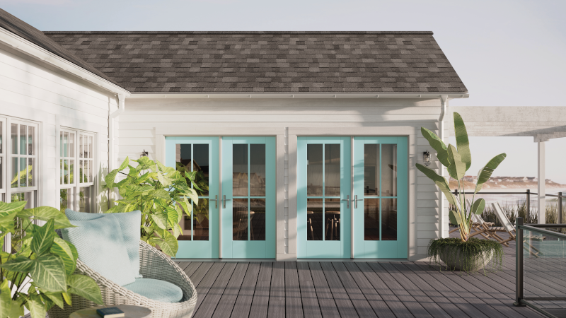 A white house with blue doors and a patio in front of it.