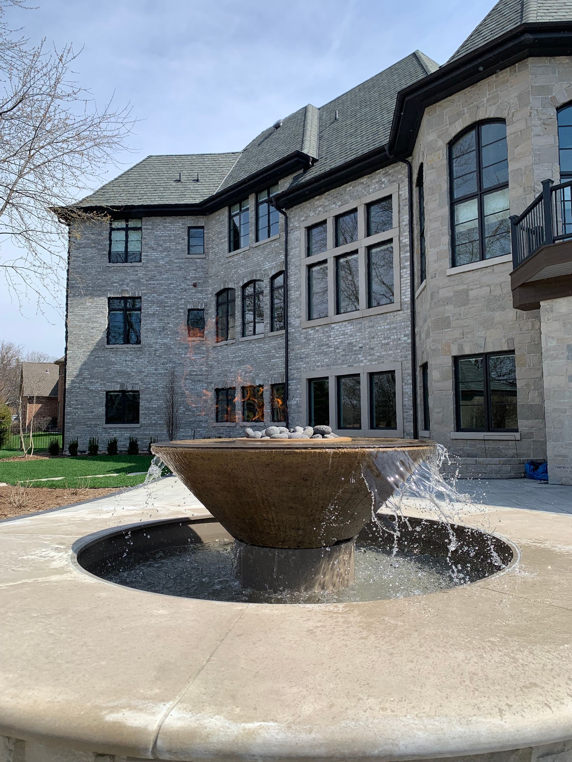 Fountain with water spraying in front of a large stone house.