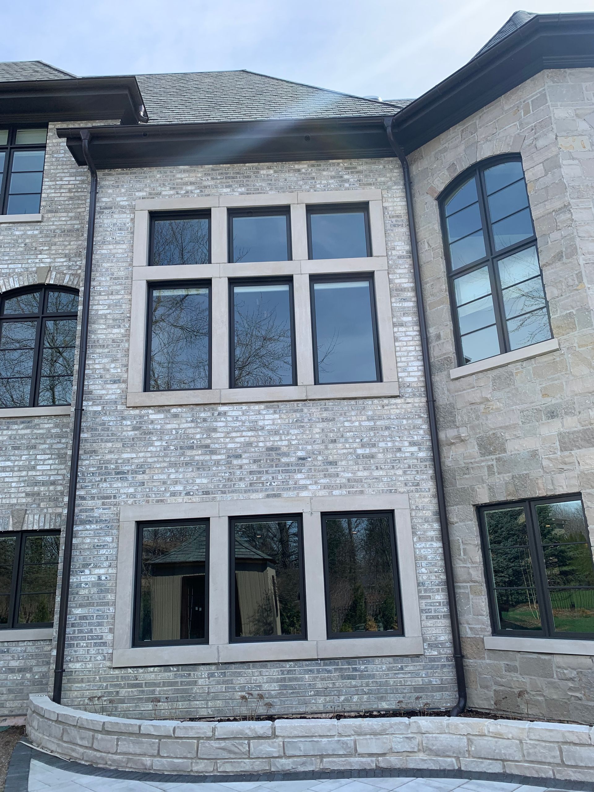 Stone building with black-framed windows. Large multi-pane windows stand out against the grey stone facade.