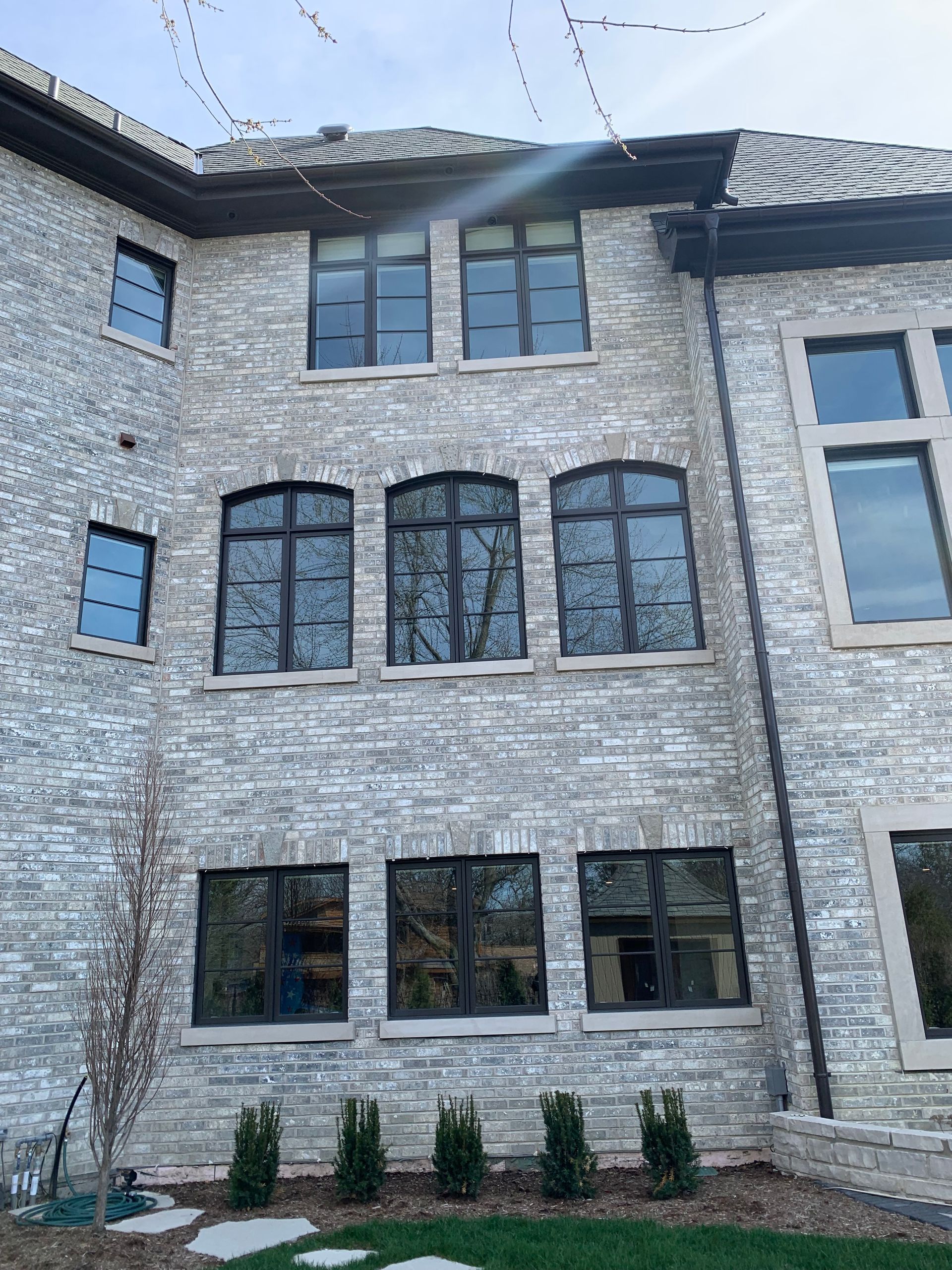 Stone facade of a large house with multiple dark-framed windows.