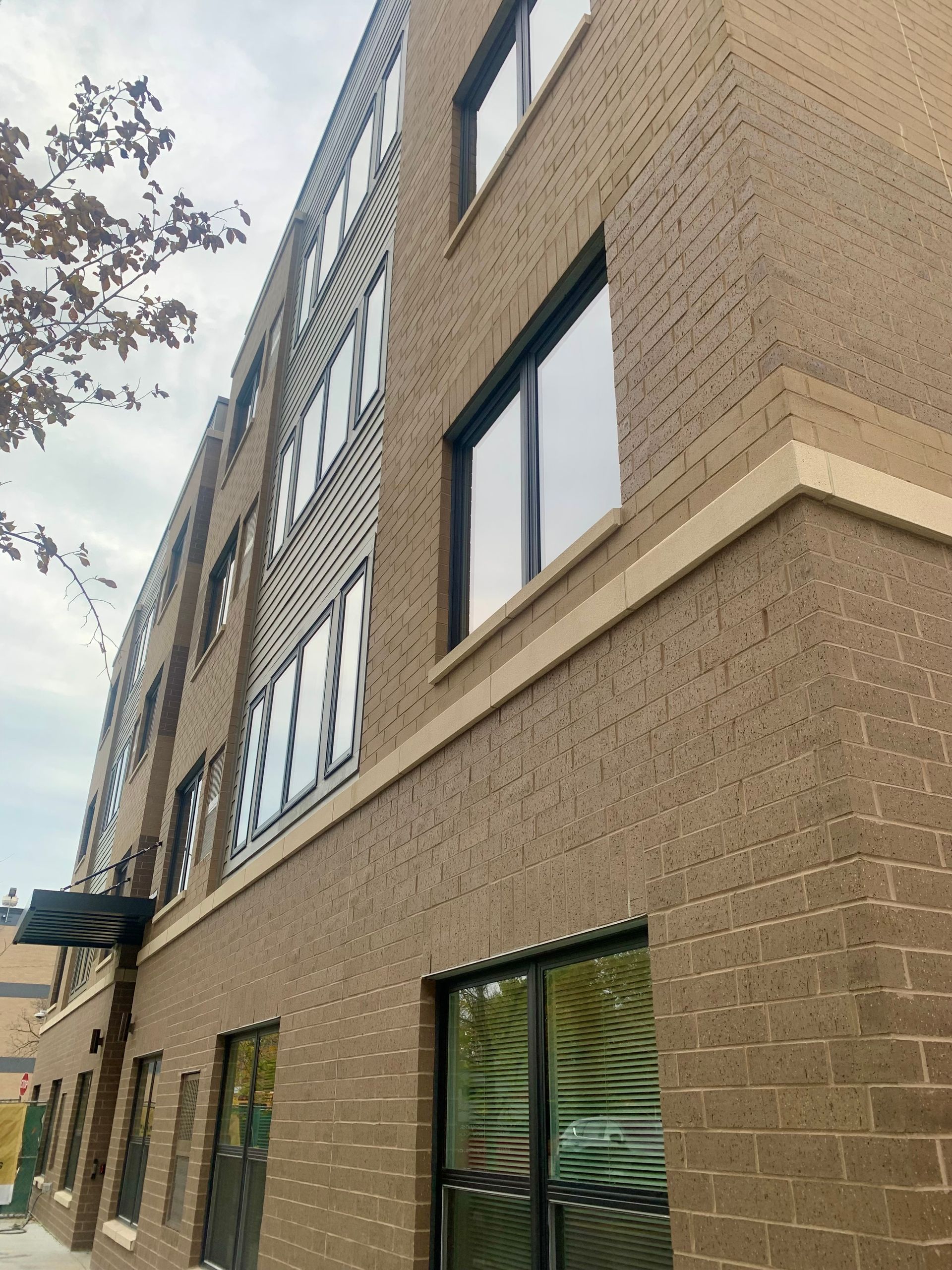 Brick building with many windows, overcast sky.