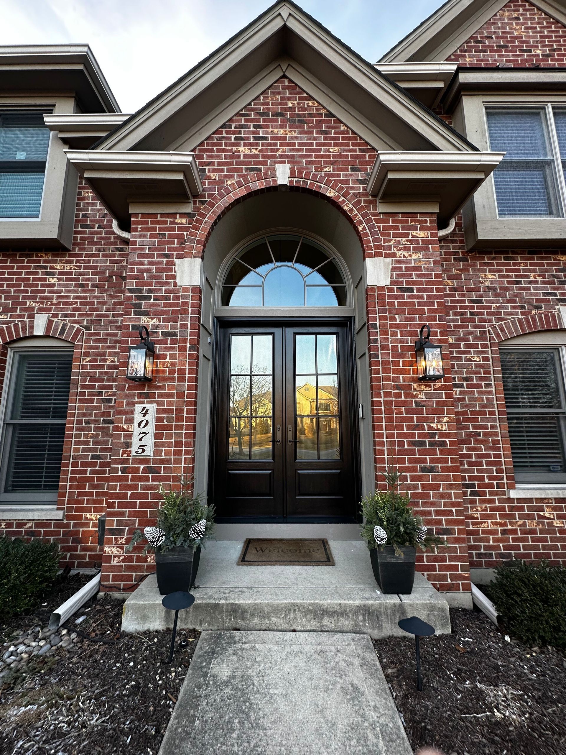Red brick house with arched entryway and black double doors.