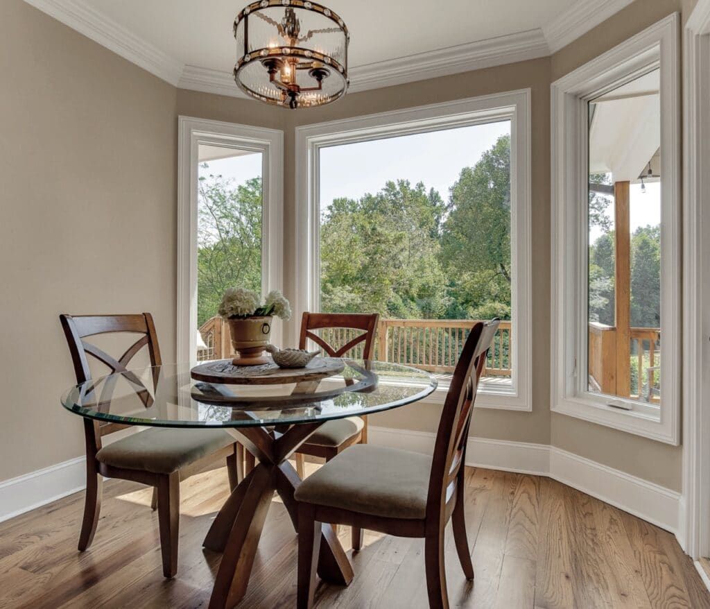 A dining room with a glass table and chairs and a large window