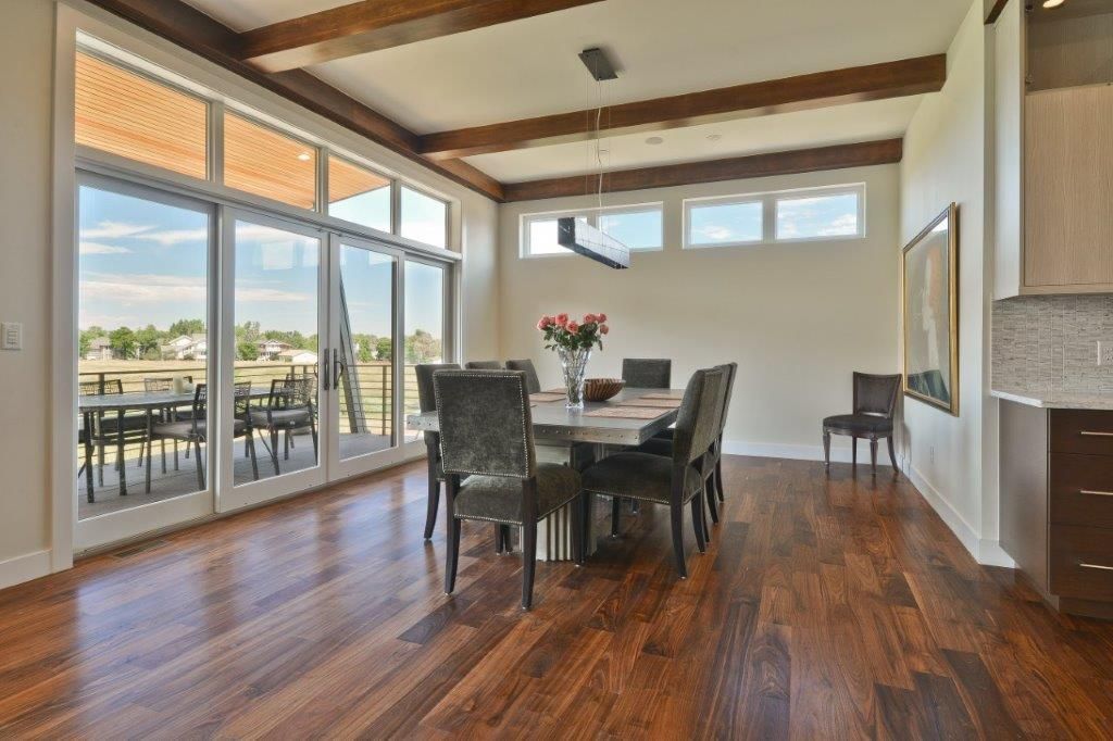 A dining room with a table and chairs and a lot of windows.