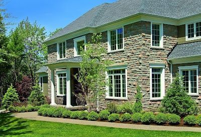 A large stone house with a lot of windows and trees in front of it