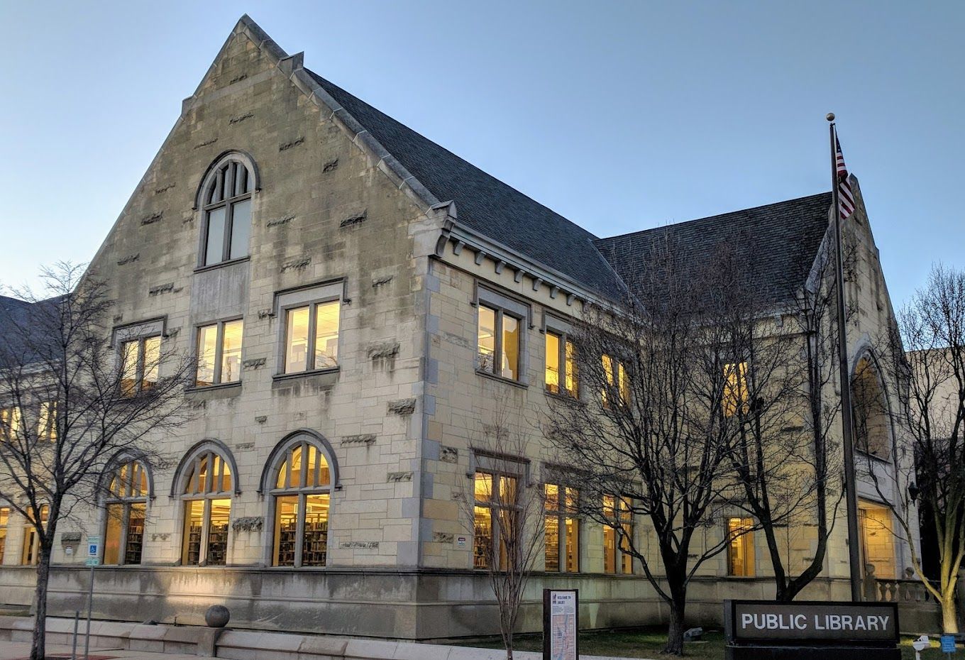 A large stone building with a sign that says public library in front of it.