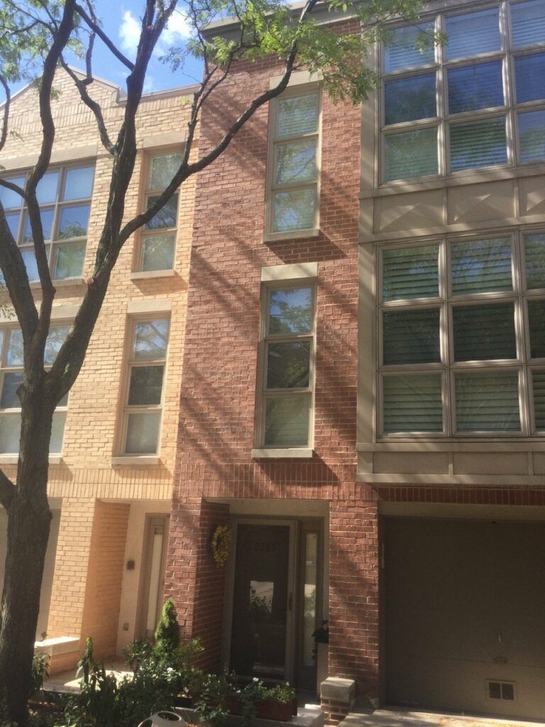 A brick building with a lot of windows and a tree in front of it