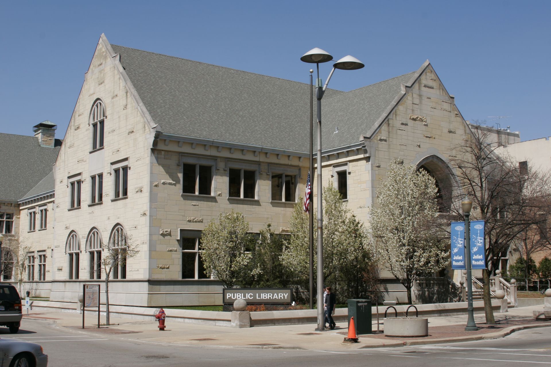 A large brick building with a gray roof is on the corner of a street