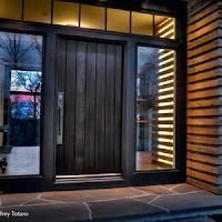 A black front door with a lot of windows and a wooden siding.