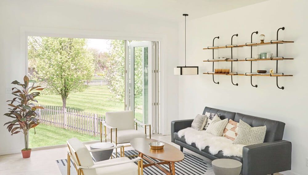 A living room with a couch , chairs , coffee table and shelves.