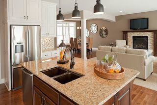 A kitchen with granite counter tops , stainless steel appliances , a sink and a refrigerator.