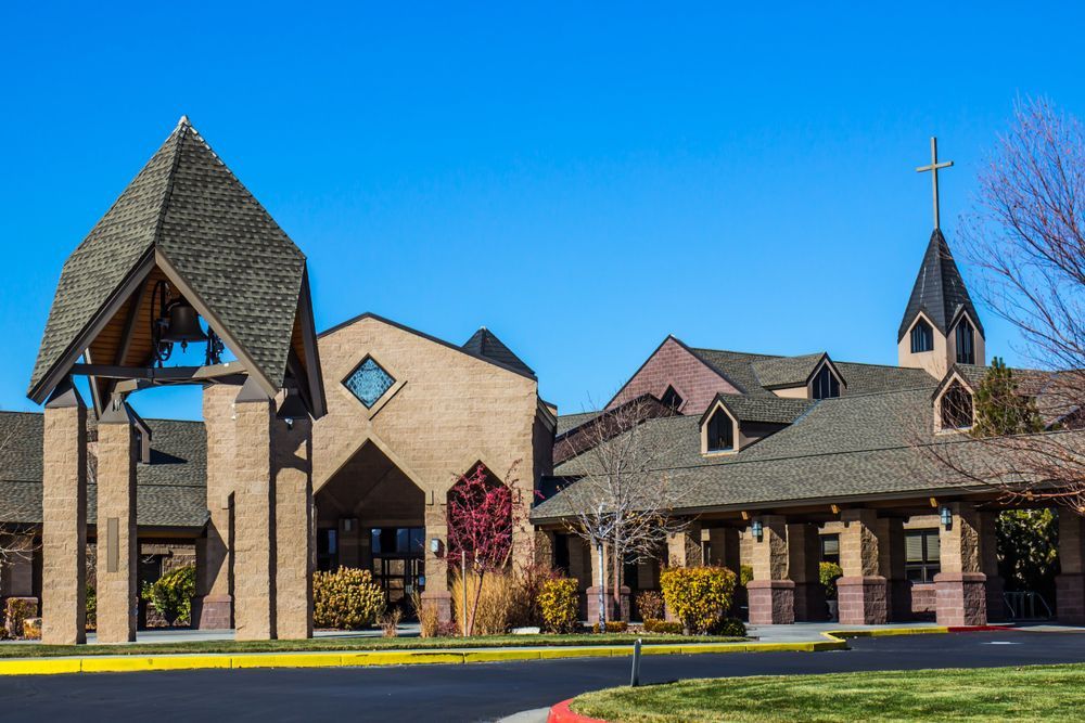 Brick church with bell tower and cross, under a clear blue sky.
